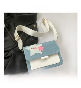 Detail of denim crossbody bag featuring star patchwork and a wide textile shoulder strap