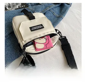 Close-up of minimalist off-white canvas crossbody bag with adjustable black shoulder strap