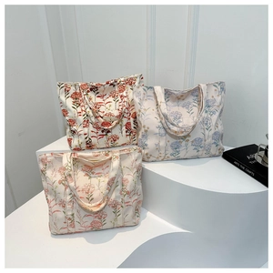 Dettaglio ravvicinato di tre borse tote in tela con motivi floreali vintage rosso, blu e rosa