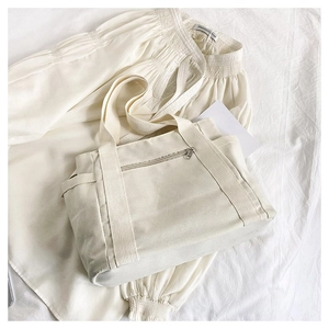 Detailed macro view of cream canvas tote bag showing front zipper pocket and wide handle