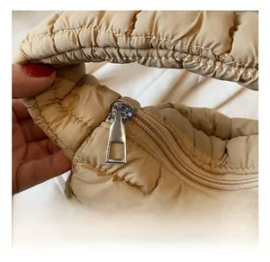 Detailed macro view of silver zipper hardware on the pleated khaki puffer bag