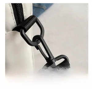 Detail of matte black metal hook and durable woven strap on off-white nylon bag