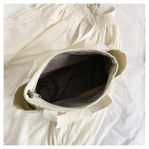 Detailed view of large canvas tote bag showing smooth metal zipper and dark fabric lining