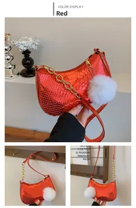 Detail view of red faux snakeskin hobo bag with gold chain and white plush ball charm