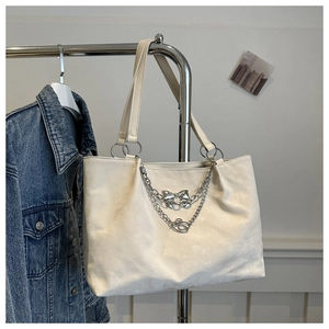 Détail du sac cabas blanc crème avec chaînes argentées et pendentif papillon élégant