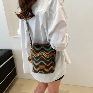 Detail of retro woven bucket bag featuring blue and yellow stripes and leather strap