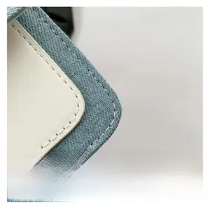 Detail shot of denim and leather patchwork with precise white stitching on the corner