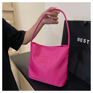 Detail of rose pink nylon tote bag featuring elegant letter embroidery on minimalist surface