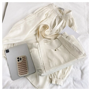 Detail of a minimalist cream canvas tote bag with front pocket and thick handles