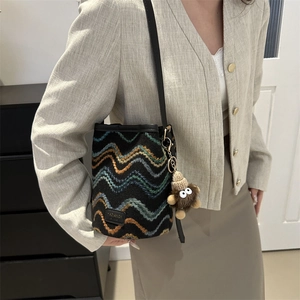 Detail showing the colorful wave pattern fabric and branded logo of the bucket bag