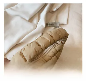 Detail shot of beige quilted cloud bag showing soft padded handles and top zipper
