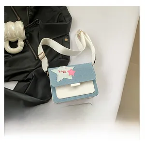 Detail of denim patchwork star shoulder bag with wide strap and mobile phone for scale