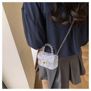 Détail du sac en gelée transparent avec poignée en perles, chaîne et motif matelassé