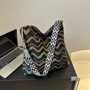 Close-up of woven velvet tote with colorful wavy stripes and wide geometric strap