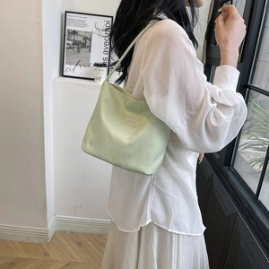 Close-up of light green nylon shoulder bag with priority and liberty embossed text