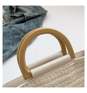 Détail de la texture en paille tressée avec bordure en cuir crème et anses rondes en résine