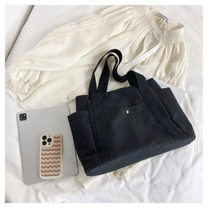 Detail showing side pockets and bronze button on a black canvas tote bag for work