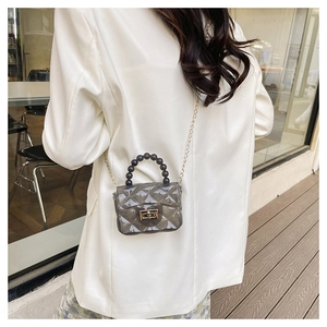 Gros plan d'un mini sac gelée gris transparent avec motif matelassé et fermoir doré