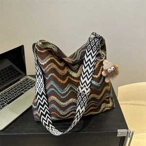 Detail of colorful striped velvet tote with geometric strap and monster charm