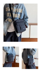 Detail view of black nylon messenger bag with front zipper and fashion label