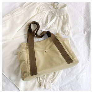 Detail of canvas tote bag with side pockets, contrast handles and retro metal snap button
