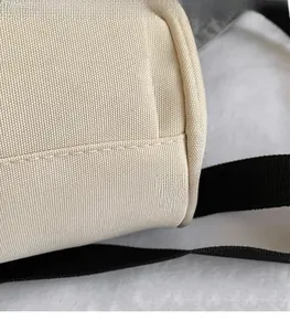 Detailopname van beige Oxford-stof met nette stiksels en zwarte riemafwerking