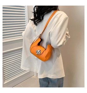 Vue détaillée d'un sac bandoulière demi-lune en cuir orange avec boucle fleur argentée