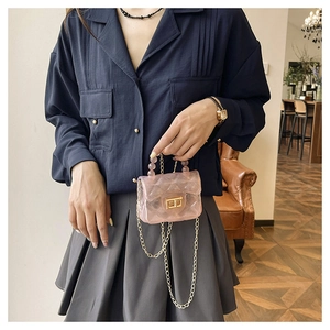 Détail d'un mini sac rose transparent à matelassage avec fermoir doré et perles