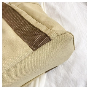Detailed close-up of khaki canvas tote bag showing neat stitching and brown woven straps