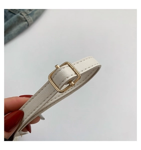 Vue détaillée de la sangle en cuir blanc avec boucle carrée dorée et coutures