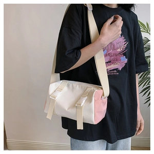 Close-up of a two-tone cylinder shoulder bag with white plastic buckles and canvas texture