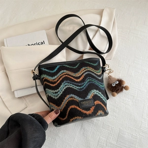 Detail view of woven bucket bag with blue orange waves and fuzzy monster charm