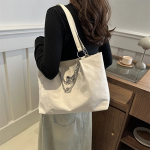 Grand sac fourre-tout beige avec chaîne argentée et nœud porté par un mannequin