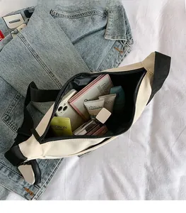 Detail view of the spacious inner compartment of the beige nylon crossbody bag with items