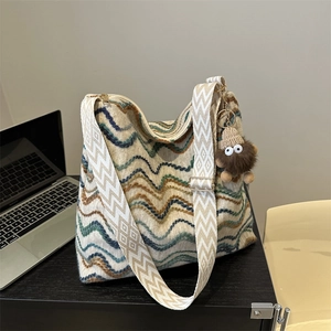 Close-up of a velvet knit tote bag with wavy patterns and a brown monster plush charm
