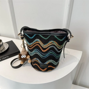 Detail of woven bucket bag with wave patterns, leather straps and plush toy charm