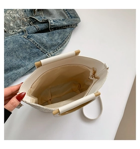 Détail du sac tressé montrant l'anse en bois, le compartiment zippé et la bandoulière