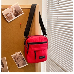 Close-up of red nylon mini crossbody bag with zipper pocket and black logo label