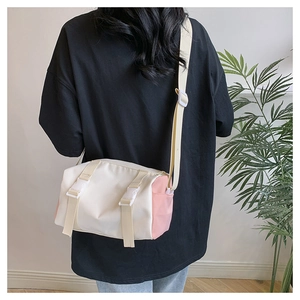 Back view of a cylinder crossbody bag in cream and pink on a stylish female model