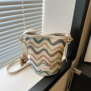 Detailed knit texture of colorful striped bucket bag with leather logo and plush charm