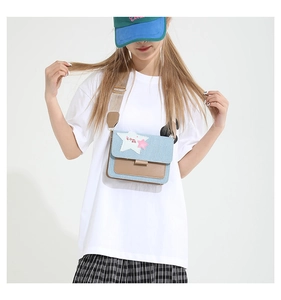Detailed view of denim and brown leather crossbody bag with colorful star patches