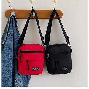 Close-up of red and black canvas shoulder bags showing functional zipper pockets and buckles
