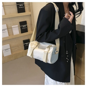 Detail view of the side profile on a white and blue cylinder crossbody bag with buckle