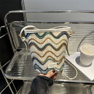 Close-up of knit wave pattern and leather trim on a bucket shoulder bag