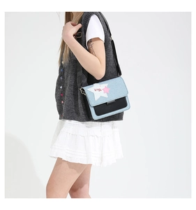 Detail of denim and leather crossbody bag featuring a white star patch and wide strap
