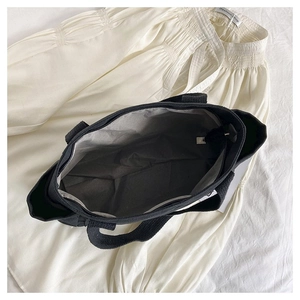 Detailed interior of a black canvas tote bag with zipper closure and grey inner lining