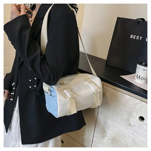Side view of bicolor beige and blue crossbody bag worn with a stylish black suit jacket