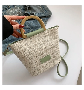 Vue de dessus du sac seau en paille avec poignée en bois et détails en cuir vert clair