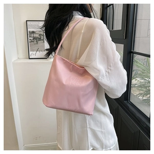 Detail of pink nylon tote bag with embroidered text and slender shoulder strap