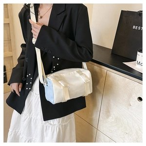 Detail view of a white and light blue cylinder crossbody bag with stylish buckles
